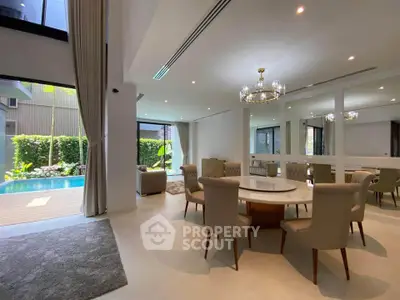 Luxurious open-plan living room with pool view, elegant dining area, and modern decor in a high-end property.