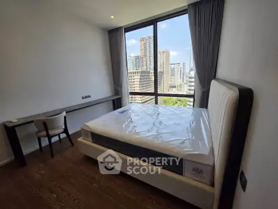 Modern bedroom with large window offering stunning city view, featuring a sleek desk and comfortable bed.