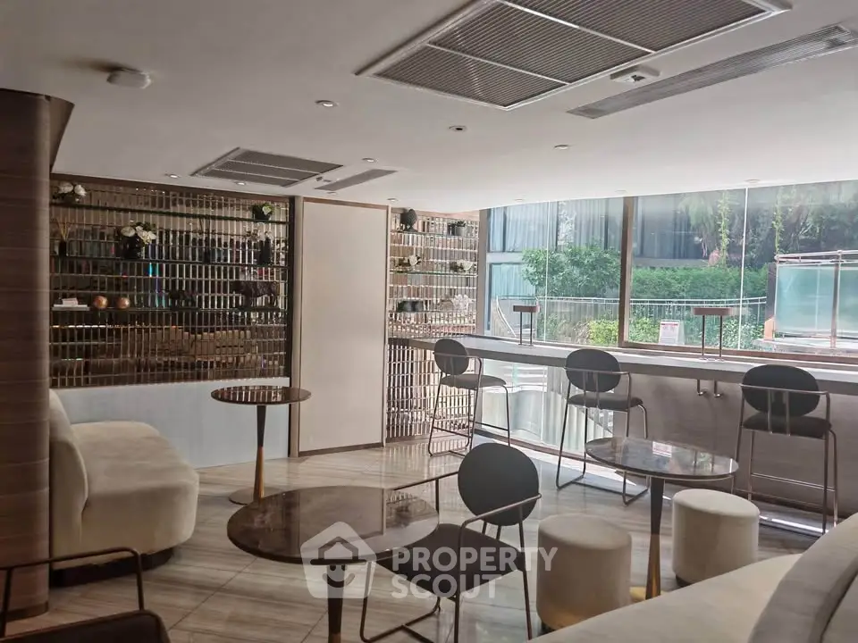 Modern lounge area with stylish seating and large windows overlooking greenery.