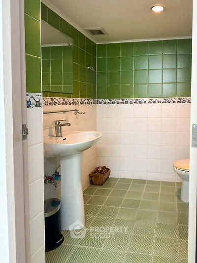 Charming bathroom with green tiles and modern fixtures, perfect for a cozy home.