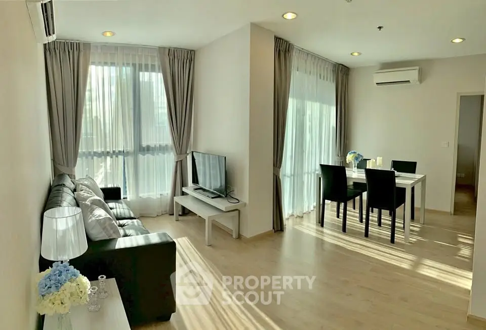 Spacious modern living room with dining area, large windows, and elegant decor in a bright apartment.