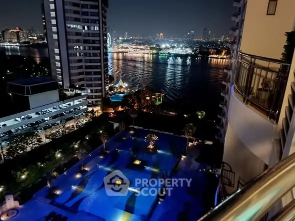 Stunning night view of city skyline and river from high-rise balcony overlooking illuminated pool area.