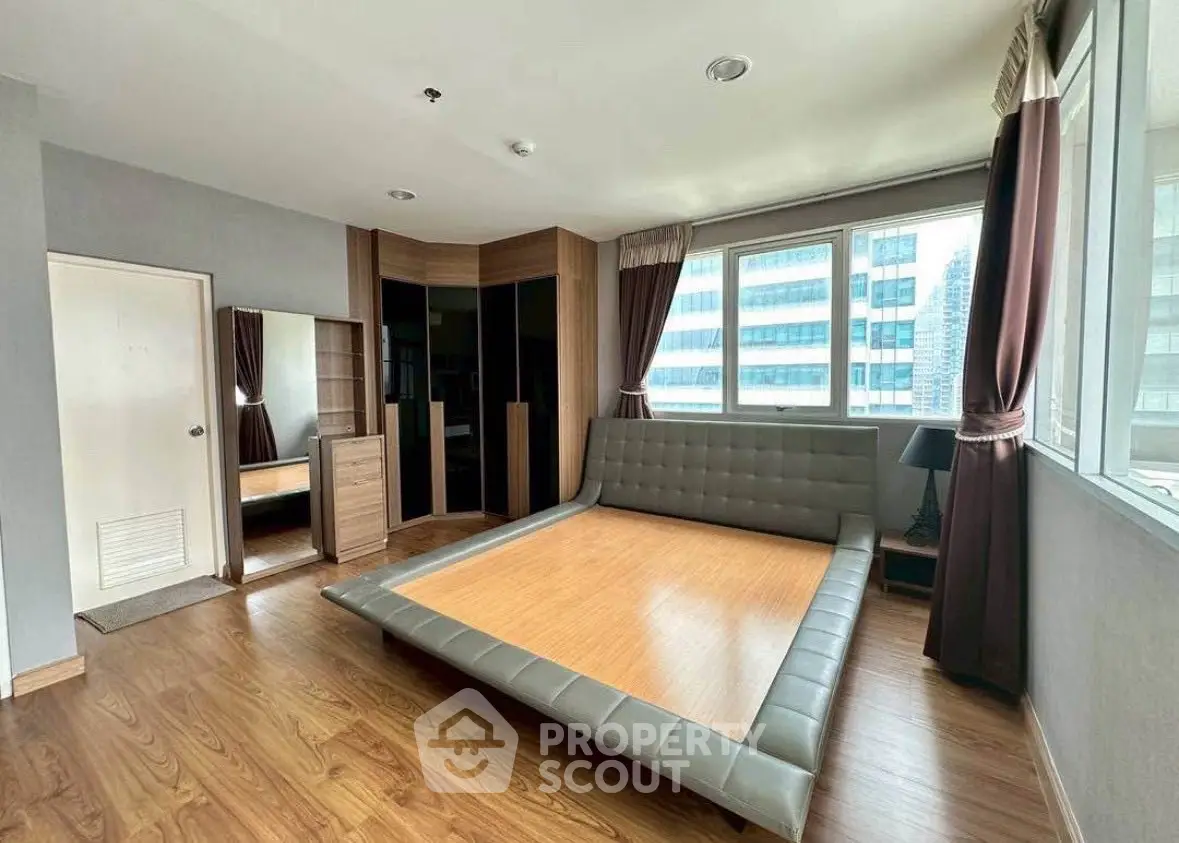 Spacious bedroom with modern design and large windows offering city views.