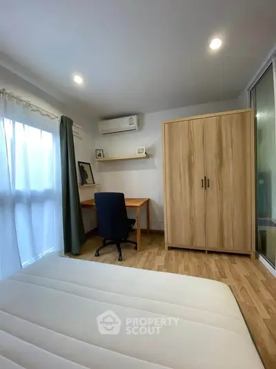 Cozy bedroom with study area, featuring wooden wardrobe and desk, ideal for modern living.