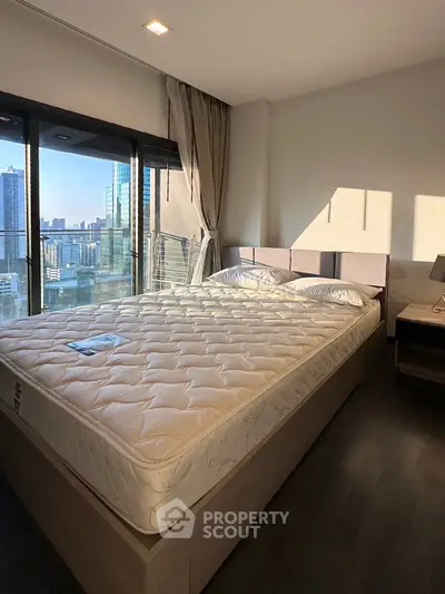 Modern bedroom with city view and large windows in a high-rise apartment.