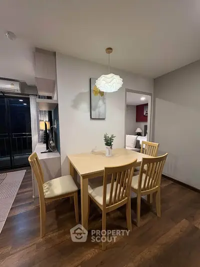 Cozy dining area with wooden table and chairs, modern lighting, and open layout to living space.