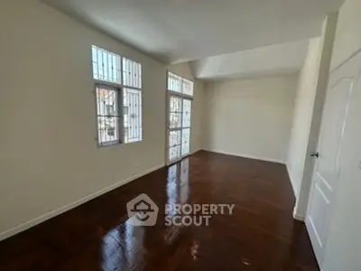 Spacious empty room with polished wooden floors and large windows