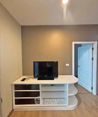 Modern living room with sleek TV stand and open door, showcasing minimalist design.
