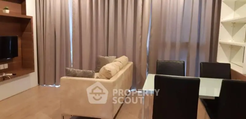 Modern living room with cozy sofa and dining area, featuring elegant curtains and wooden flooring.