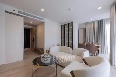 Modern living room with elegant furniture and dining area, featuring neutral tones and stylish decor.