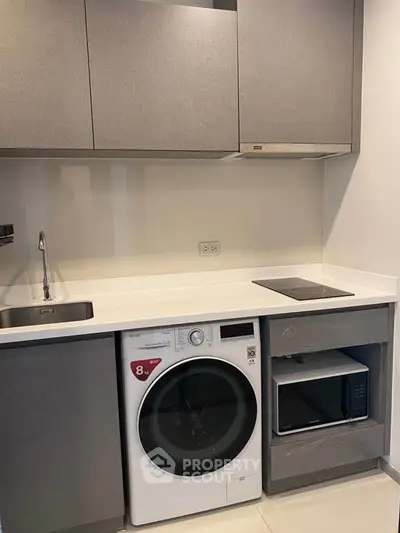 Modern kitchen with sleek cabinetry, washing machine, and microwave in compact layout.