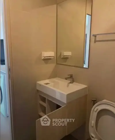 Compact bathroom with modern sink and toilet, featuring a sleek mirror and neutral tones.