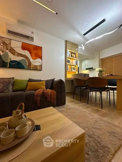 Modern living room with cozy seating and stylish decor, open layout to dining area and kitchen.