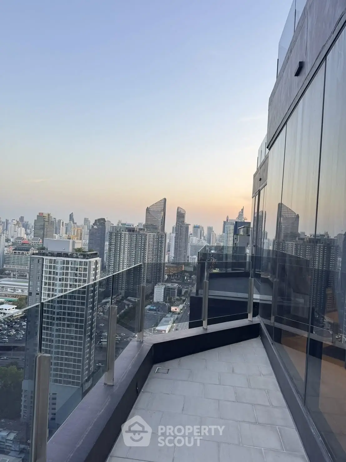 Stunning cityscape view from a modern high-rise balcony with glass railings, perfect for urban living.