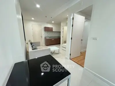 Sleek modern studio apartment with glossy finishes, featuring a combined living and sleeping area, a full kitchen with wooden cabinetry, and ample natural light.