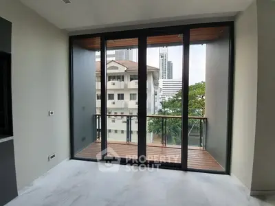 Modern apartment with floor-to-ceiling windows and balcony view of cityscape.