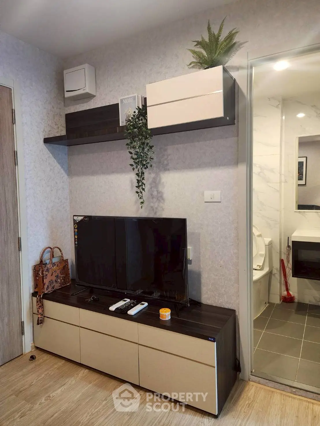 Modern living room with TV unit and bathroom view, stylish decor and wooden flooring.