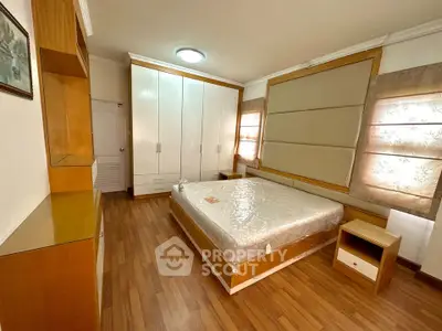 Spacious bedroom with wooden flooring and ample storage in modern apartment.