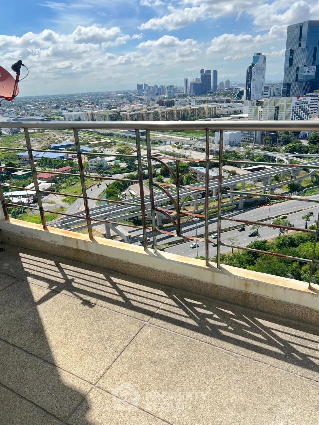 Stunning high-rise balcony view overlooking cityscape with modern skyscrapers and lush greenery.