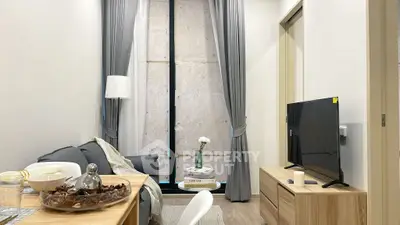 Modern living room with stylish decor and natural light, featuring a cozy sofa and sleek TV setup.