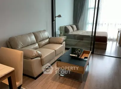 Modern studio apartment with cozy living area and bedroom separated by glass partition.