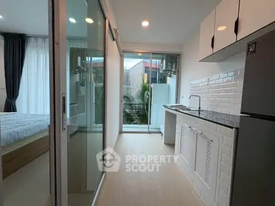 Modern apartment with sleek kitchen and cozy bedroom, featuring large windows and stylish decor.