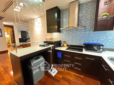 Modern kitchen with sleek cabinetry, glass backsplash, and hardwood floors in a stylish apartment.