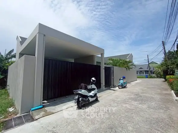 Modern residential building with driveway and parked scooters under clear sky.