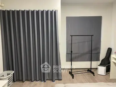 Spacious bedroom with modern gray curtains and clothing rack, ideal for stylish living.