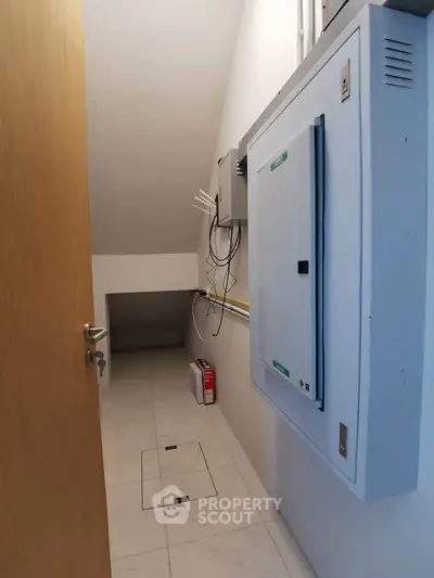 Compact storage room with electrical panel and tiled floor, ideal for utility use.