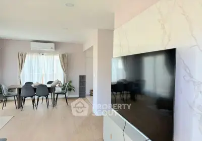 Spacious modern living room with large TV and dining area, perfect for family gatherings.