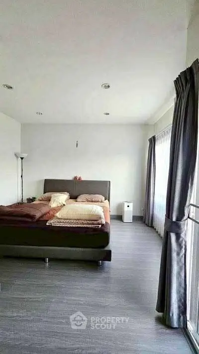 Spacious bedroom with modern decor and large windows for natural light.