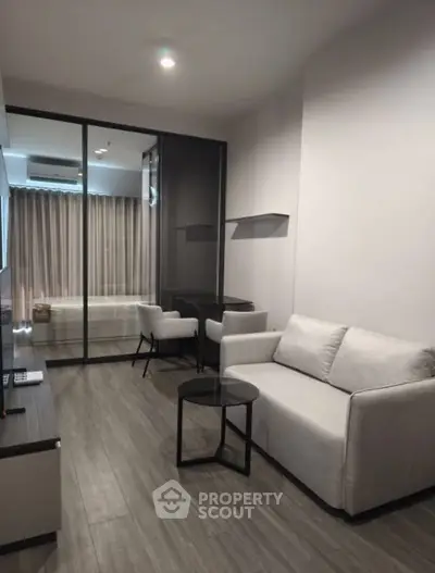 Modern living room with sleek design and glass partition, featuring cozy sofa and stylish decor.