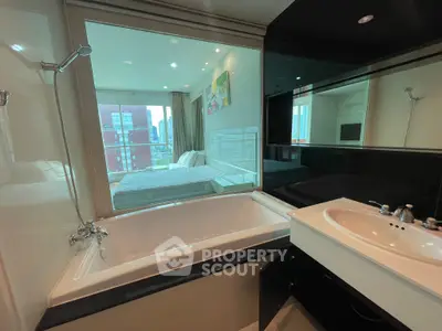 Modern bathroom with bathtub and glass wall overlooking a stylish bedroom in a high-rise apartment.