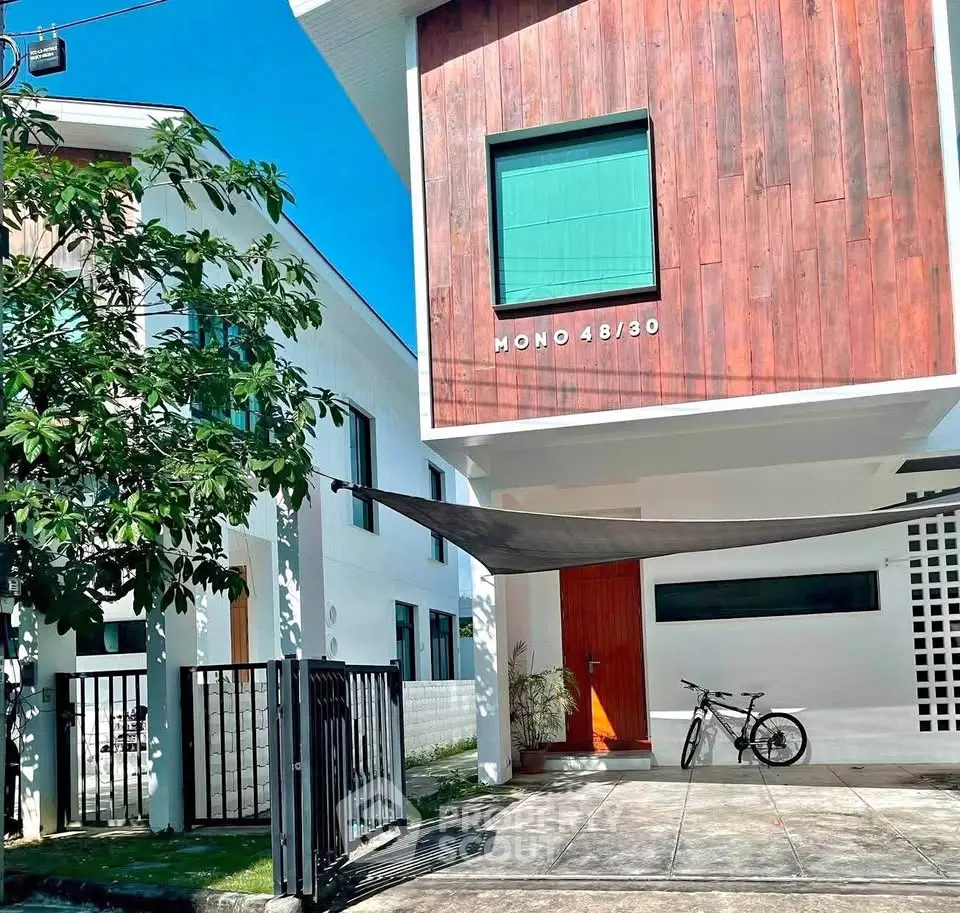 Modern two-story house with wooden facade and bike in driveway, perfect for urban living.