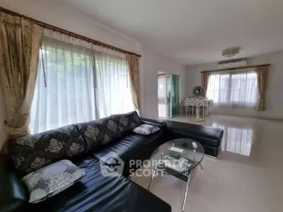 Spacious living room with elegant black sofa and large windows for natural light.