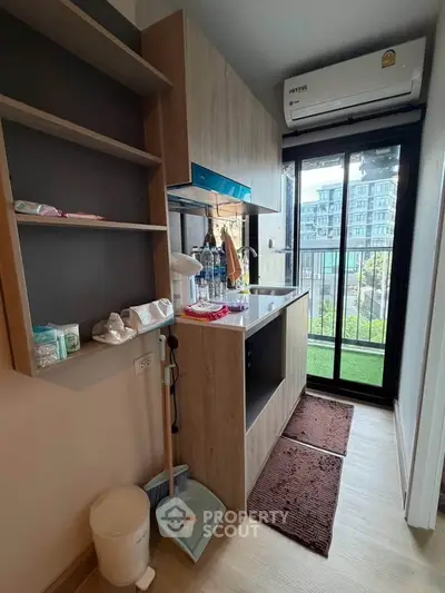 Compact kitchen with modern appliances and balcony view in urban apartment