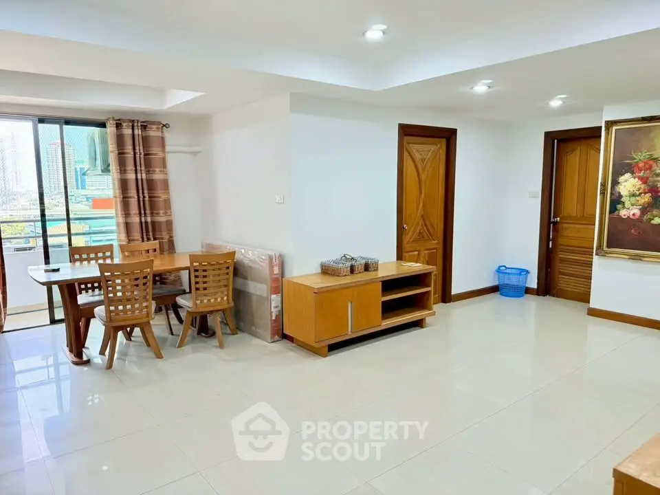Spacious living room with dining area and balcony view in modern apartment.