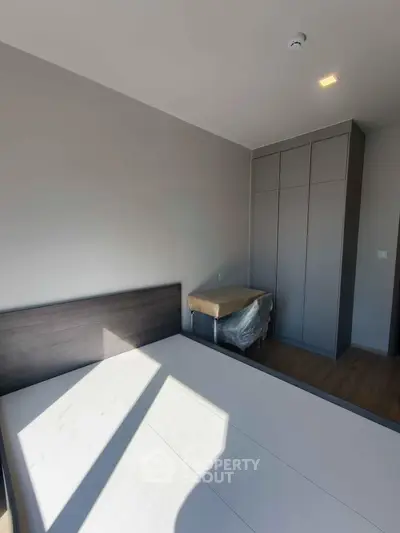 Modern bedroom with sleek wardrobe and natural light in contemporary apartment.