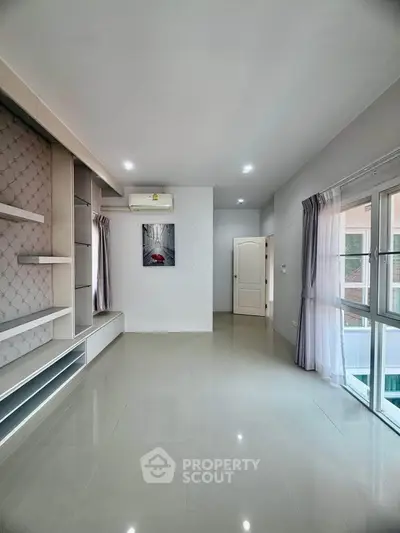 Spacious modern living room with large windows and elegant built-in shelving.