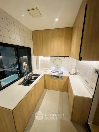 Modern kitchen with sleek wooden cabinets and gas stove in a compact layout.