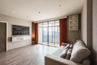 Spacious modern living room with balcony and city view, featuring stylish decor and ample natural light.