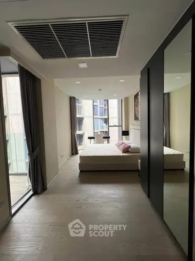 Modern bedroom with large windows and balcony access in a stylish apartment.