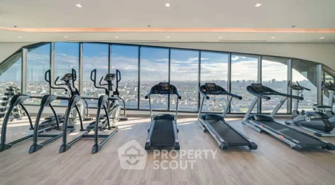 Luxury gym with panoramic city views and modern equipment in high-rise building.
