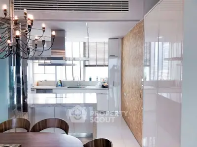 Modern kitchen with sleek design and open layout, featuring a stylish chandelier and ample natural light.