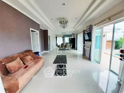 Spacious living room with elegant decor and large windows opening to a patio, perfect for entertaining.
