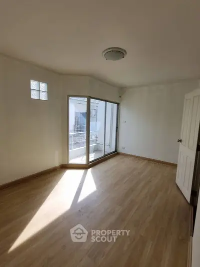 Bright empty room with wooden flooring and balcony access