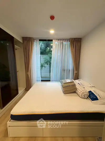 Cozy bedroom with large window and modern furnishings, perfect for relaxation and comfort.
