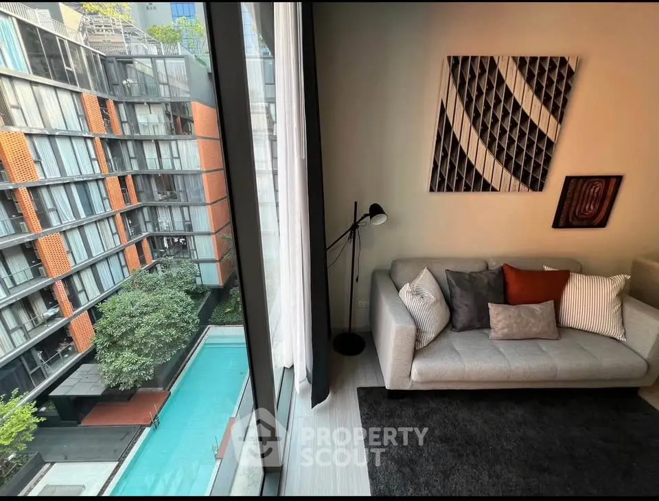 Modern living room with large window overlooking pool and contemporary decor.