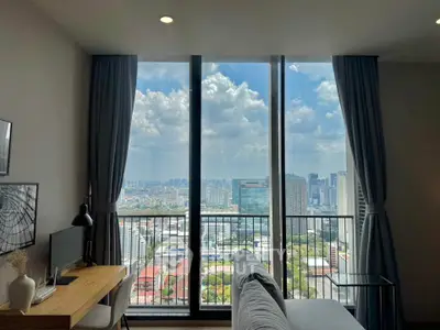 Stunning city view from modern living room with floor-to-ceiling windows and cozy workspace.
